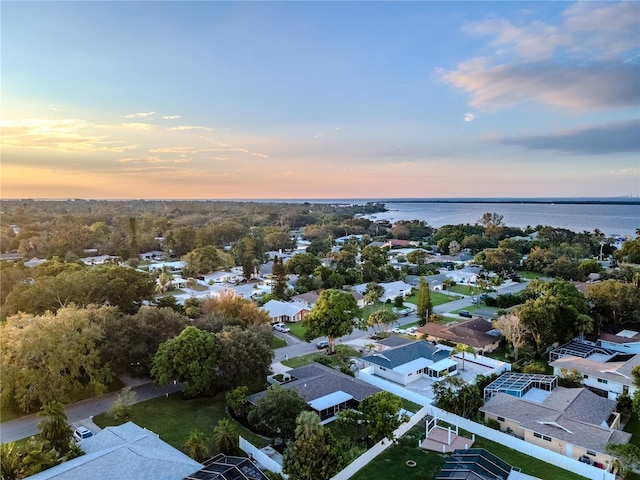 aerial view at dusk with a water view and a residential view