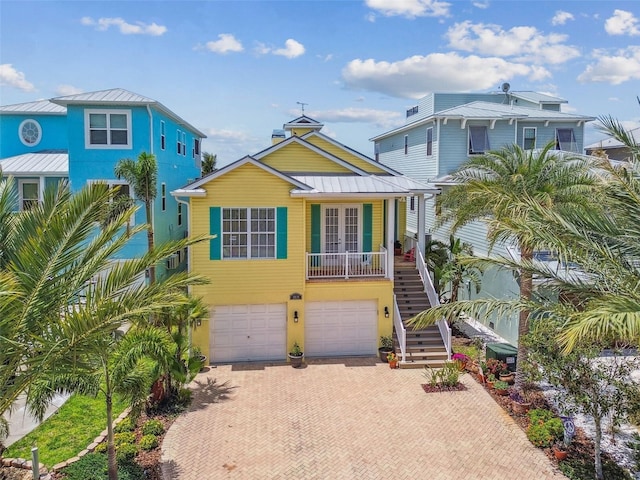 1326 Apollo Beach Blvd S, Apollo Beach, FL 33572 - beach home featuring stairs, an attached garage, a standing seam roof, decorative driveway, and french doors