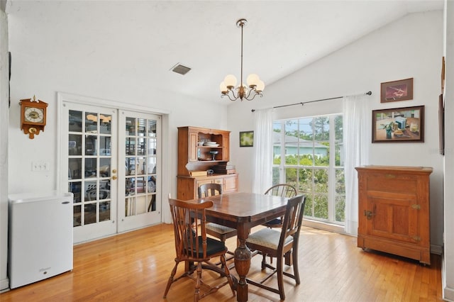 dining space with visible vents, an inviting chandelier, vaulted ceiling, and light wood-type flooring
