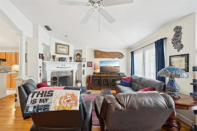 living area featuring a ceiling fan, light wood-style flooring, visible vents, decorative columns, and vaulted ceiling