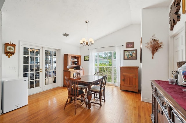 dining room with a notable chandelier, light wood finished floors, french doors, vaulted ceiling, and visible vents