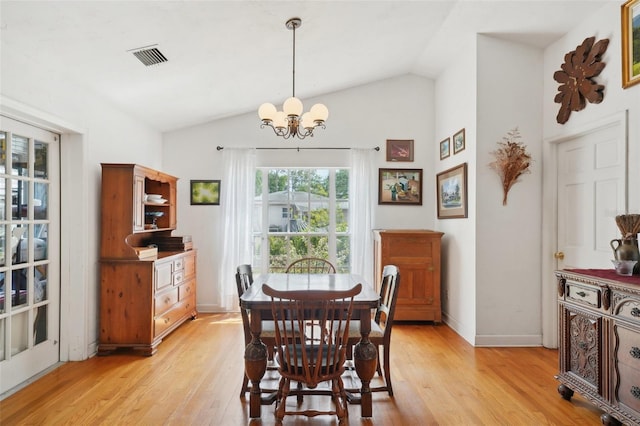 dining area featuring light wood-style floors, an inviting chandelier, vaulted ceiling, and visible vents