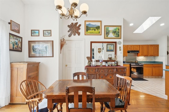 dining area featuring recessed lighting, a skylight, a notable chandelier, and light wood-style flooring