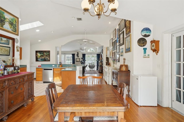 dining area with ceiling fan with notable chandelier, lofted ceiling with skylight, light wood-type flooring, visible vents, and recessed lighting
