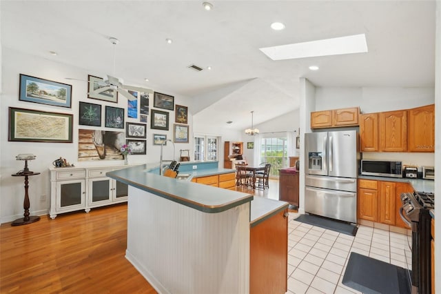 kitchen featuring vaulted ceiling with skylight, a large island, visible vents, stainless steel appliances, and recessed lighting