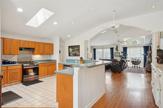 kitchen featuring arched walkways, decorative columns, appliances with stainless steel finishes, and under cabinet range hood