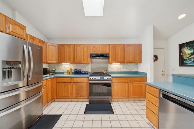 kitchen with light countertops, stainless steel appliances, decorative backsplash, and lofted ceiling with skylight