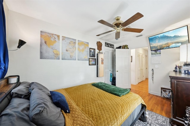 bedroom featuring a ceiling fan, visible vents, and wood finished floors