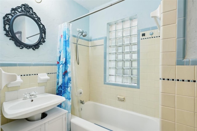 full bathroom featuring a sink, shower / tub combo, and tile walls