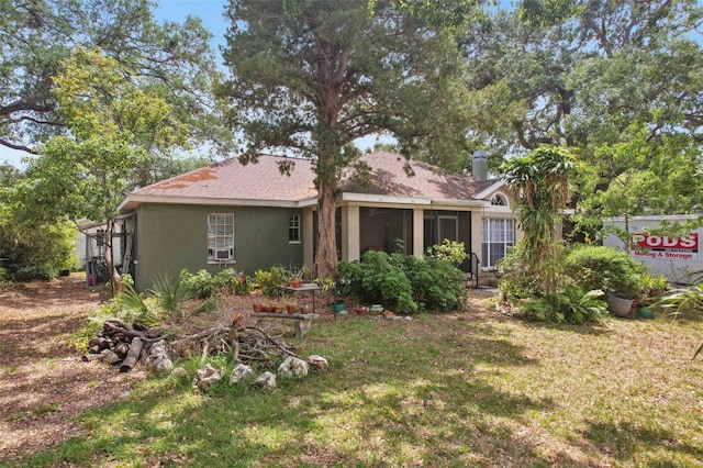 back of property featuring a sunroom, stucco siding, and a yard