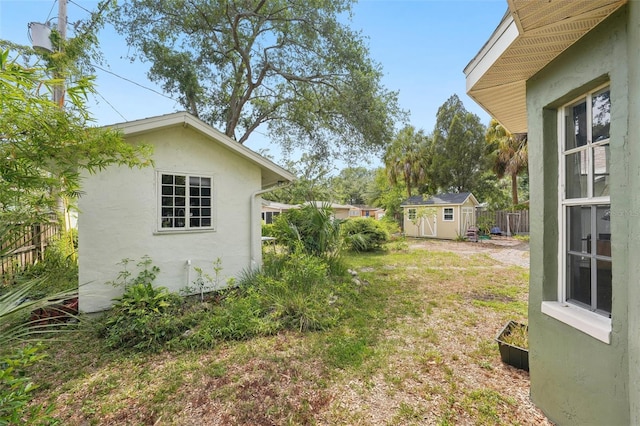 view of yard with a storage unit, fence, and an outbuilding