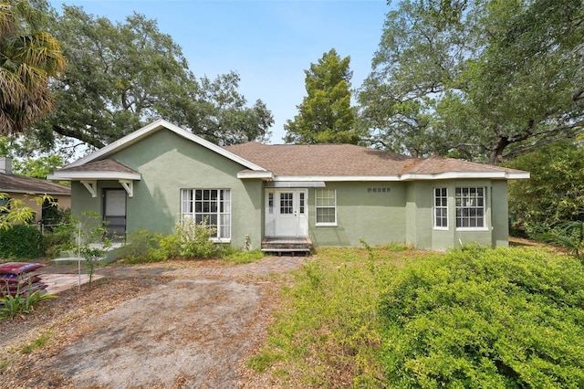 single story home featuring roof with shingles and stucco siding