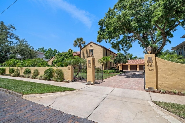 view of front facade with a fenced front yard, a gate, a garage, decorative driveway, and stucco siding