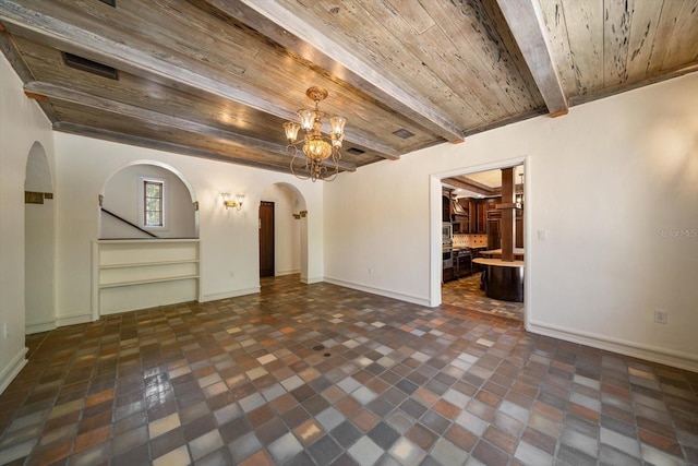 unfurnished living room with arched walkways, wooden ceiling, baseboards, beamed ceiling, and a notable chandelier