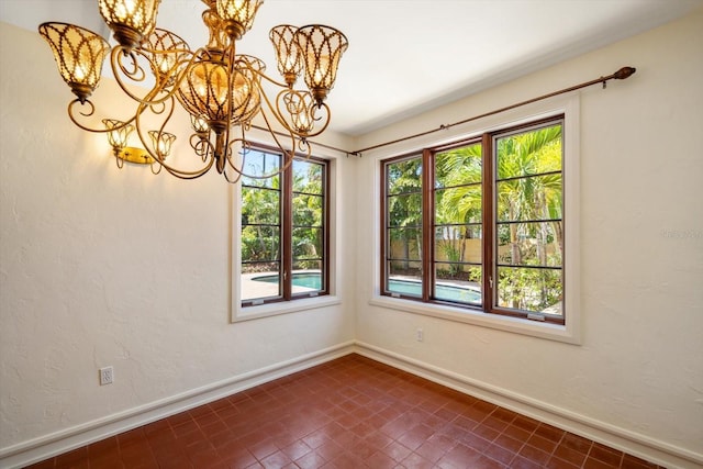 unfurnished room with plenty of natural light, baseboards, and a chandelier