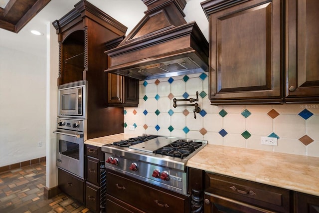 kitchen with custom range hood, baseboards, dark brown cabinets, and stainless steel appliances