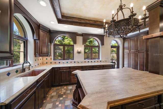 interior space featuring backsplash, an inviting chandelier, a healthy amount of sunlight, and a sink