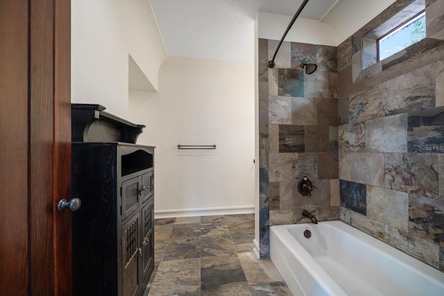 bathroom with baseboards, stone finish flooring, washtub / shower combination, and vanity