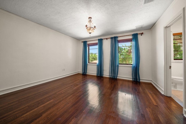 empty room with a textured ceiling, visible vents, wood finished floors, baseboards, and an inviting chandelier