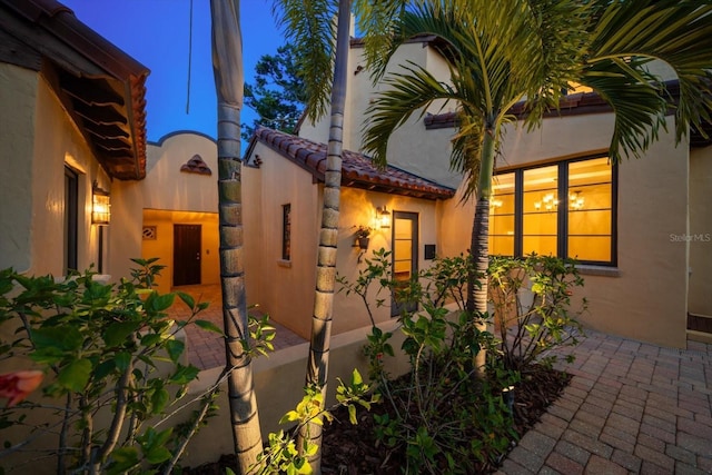 view of side of property featuring stucco siding and a tile roof