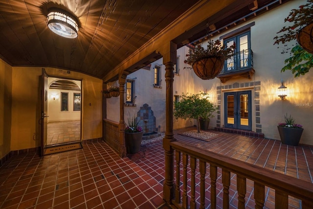 entrance to property featuring a balcony, stucco siding, and french doors