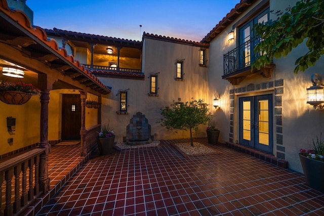 patio terrace at dusk with french doors and a balcony