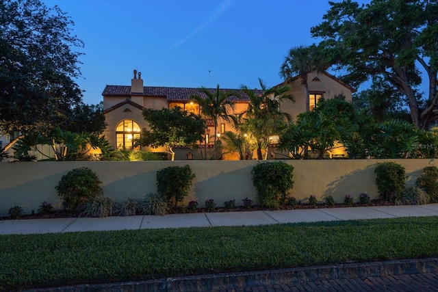 view of front of home featuring stucco siding, a fenced front yard, and a chimney