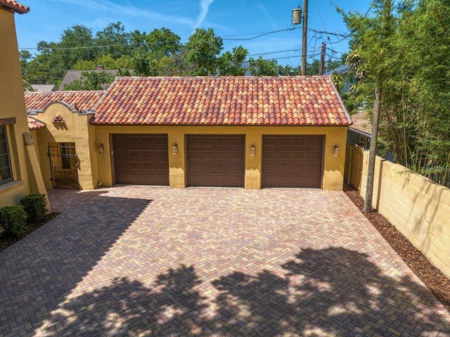 garage featuring decorative driveway and fence
