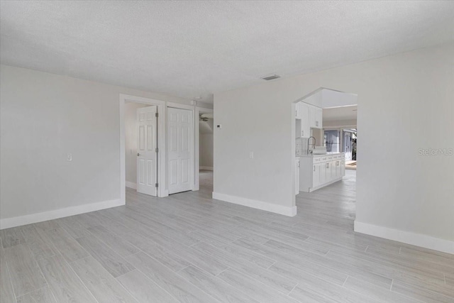 2728 58th St S, Gulfport, FL 33707 - empty room featuring baseboards, light wood-type flooring, and a textured ceiling
