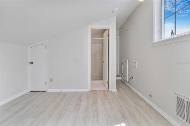 2728 58th St S, Gulfport, FL 33707 - unfurnished bedroom with light wood finished floors, a spacious closet, vaulted ceiling, baseboards, and a closet