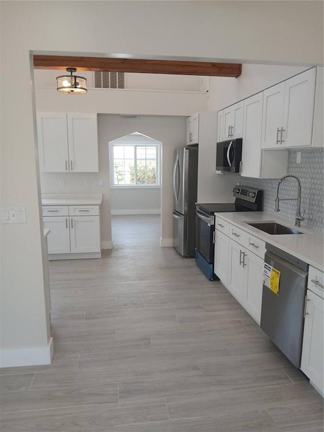 2728 58th St S, Gulfport, FL 33707 - kitchen featuring stainless steel appliances, a sink, baseboards, backsplash, and white cabinetry