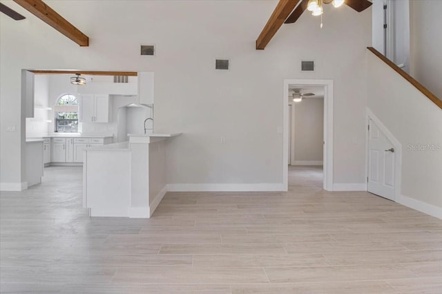 2728 58th St S, Gulfport, FL 33707 - unfurnished living room featuring ceiling fan, beam ceiling, high vaulted ceiling, light wood-type flooring, and baseboards