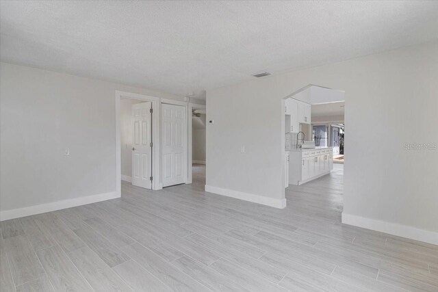 2728 58th St S, Gulfport, FL 33707 - spare room with baseboards, a sink, light wood finished floors, and a textured ceiling