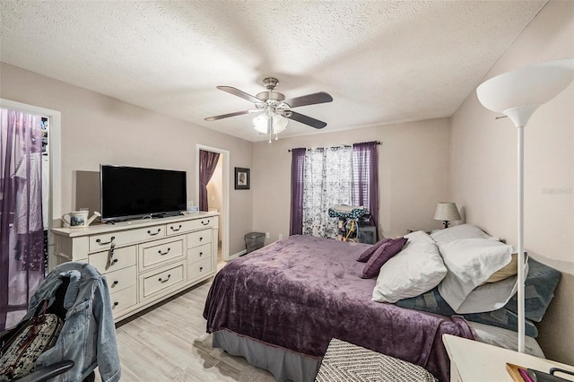 bedroom with a textured ceiling, a ceiling fan, and light wood-style flooring
