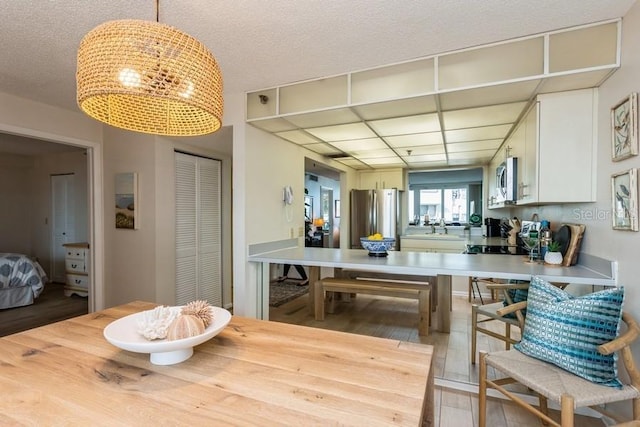 17900 Gulf Blvd Unit 1B, Redington Shores, FL 33708 - dining space featuring light wood finished floors, a chandelier, and a textured ceiling