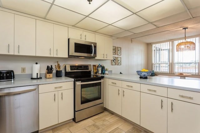 17900 Gulf Blvd Unit 1B, Redington Shores, FL 33708 - kitchen featuring appliances with stainless steel finishes, a peninsula, light countertops, white cabinets, and a paneled ceiling