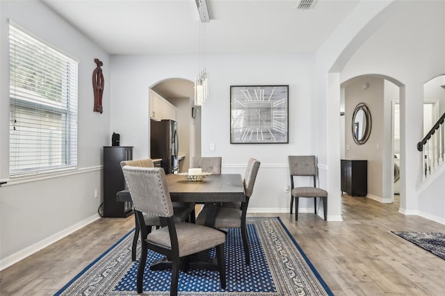 3046 Donington Castle Ln, Land O Lakes, FL 34638 - dining room with light wood-type flooring, arched walkways, washer / dryer, baseboards, and stairway