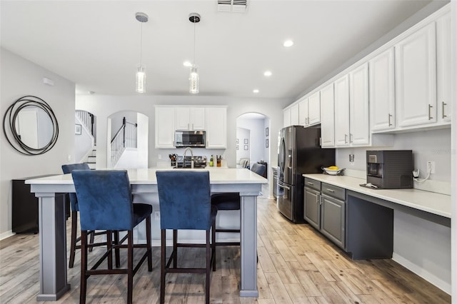 3046 Donington Castle Ln, Land O Lakes, FL 34638 - kitchen featuring stainless steel appliances, arched walkways, white cabinets, light wood-style flooring, and recessed lighting