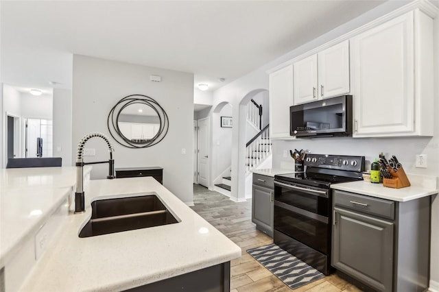 3046 Donington Castle Ln, Land O Lakes, FL 34638 - kitchen featuring black / electric stove, a sink, light wood-style flooring, gray cabinets, and white cabinets