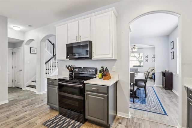 3046 Donington Castle Ln, Land O Lakes, FL 34638 - kitchen with arched walkways, black range with electric stovetop, gray cabinets, light wood finished floors, and light countertops