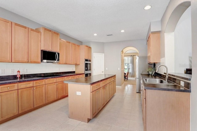 808 Hickory Glen Dr, Seffner, FL 33584 - kitchen with appliances with stainless steel finishes, arched walkways, a kitchen island, dark countertops, and light tile patterned floors