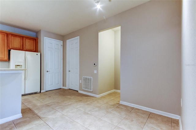 kitchen featuring visible vents, baseboards, light countertops, light tile patterned floors, and white fridge with ice dispenser