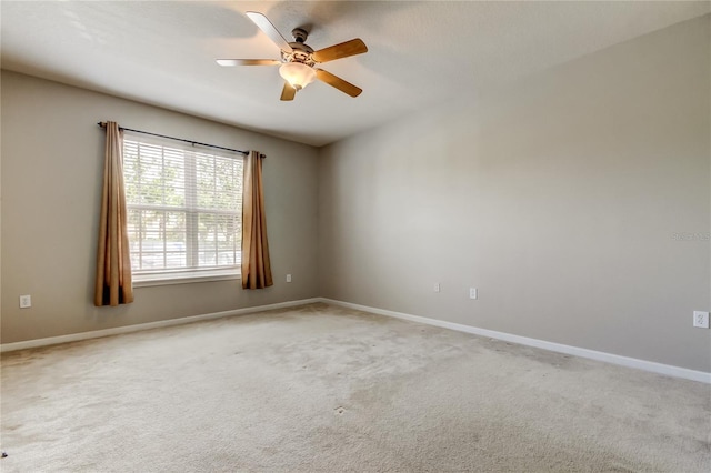 empty room with ceiling fan, light colored carpet, and baseboards