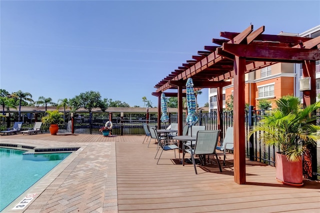 deck with fence, a pergola, a community pool, and outdoor dining space