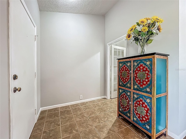 interior space featuring baseboards, tile patterned flooring, and a textured ceiling