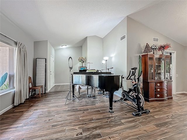 living area featuring baseboards, visible vents, wood finished floors, and lofted ceiling