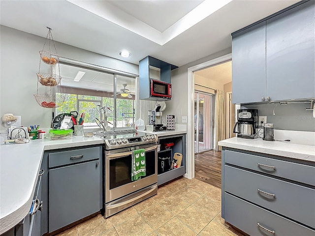kitchen with a ceiling fan, open shelves, stainless steel range with electric cooktop, light countertops, and gray cabinetry