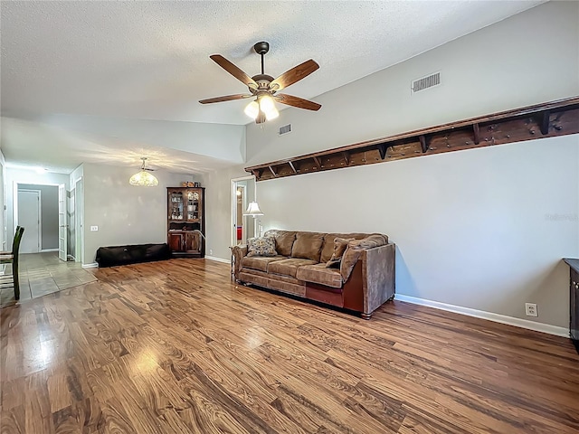 living area featuring visible vents, baseboards, ceiling fan, and wood finished floors