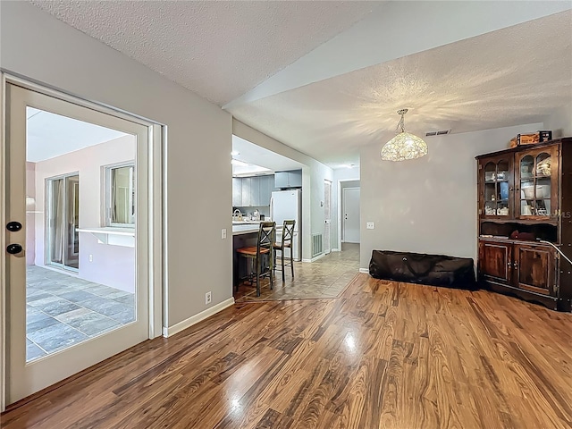 interior space with a textured ceiling, a chandelier, wood finished floors, and visible vents