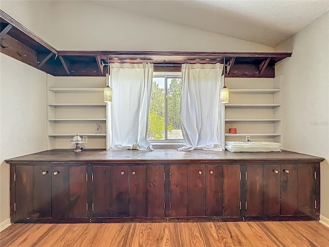 unfurnished office featuring baseboards, lofted ceiling, and wood finished floors